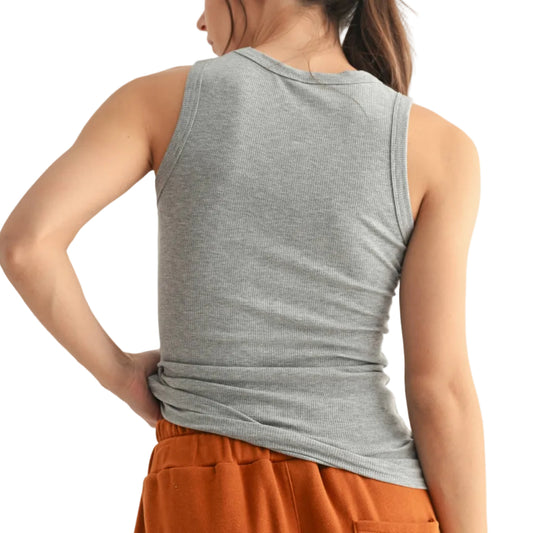 Woman wearing a gray tank top and orange pants on a plain background