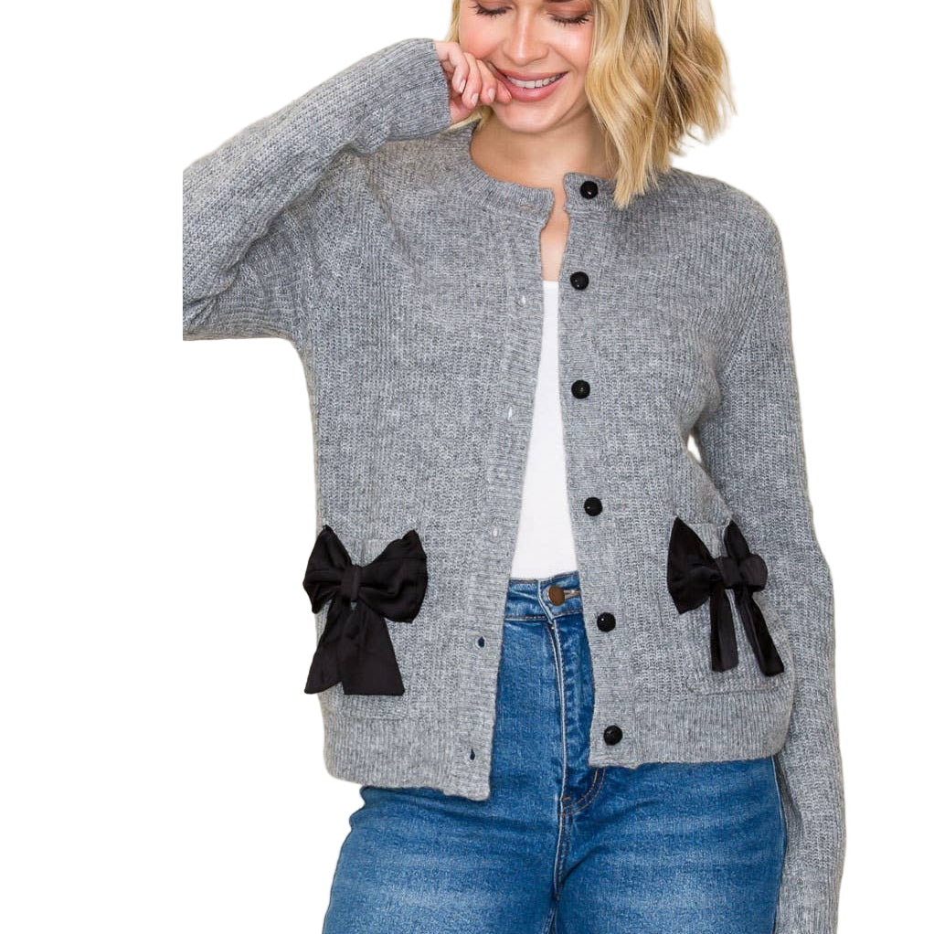 Woman wearing a gray cardigan with black bow details on a plain background