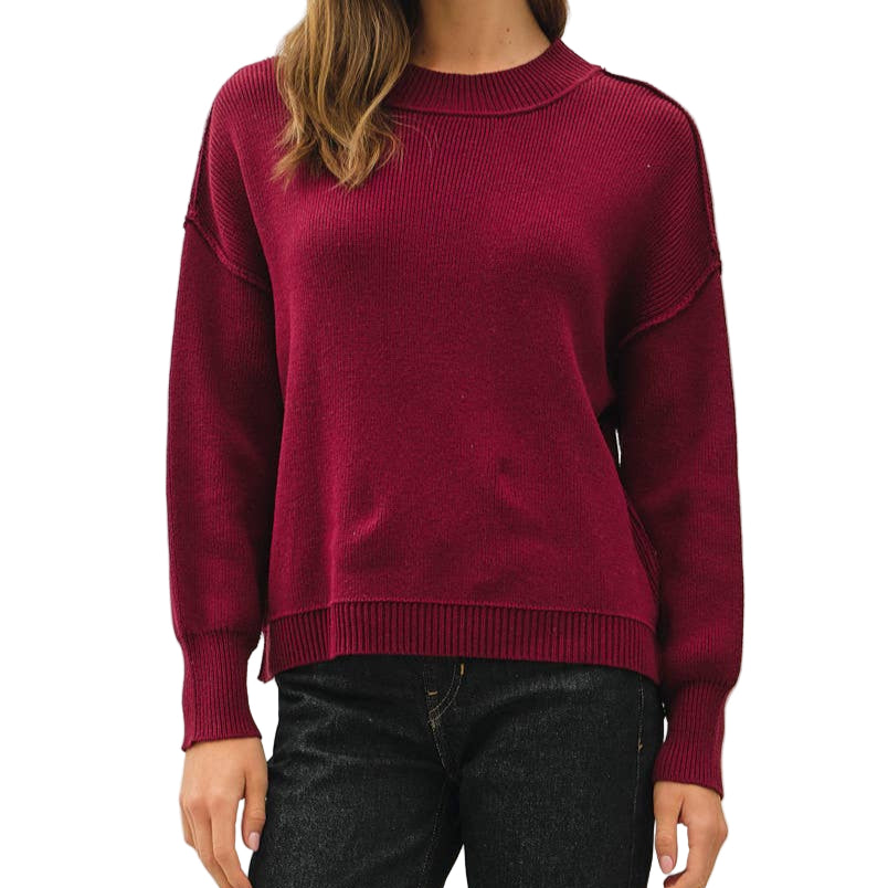 Woman wearing a burgundy sweater and black pants on a white background