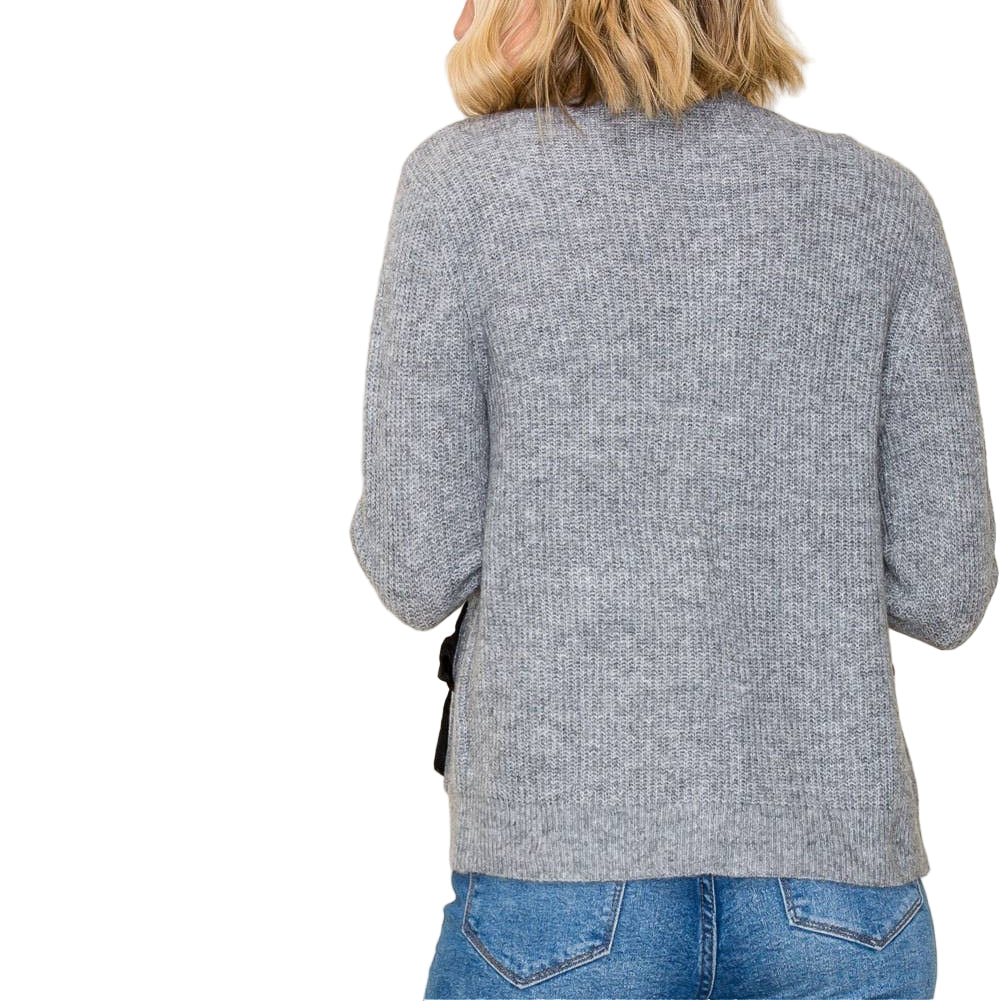 Person wearing a gray sweater and blue jeans against a white background