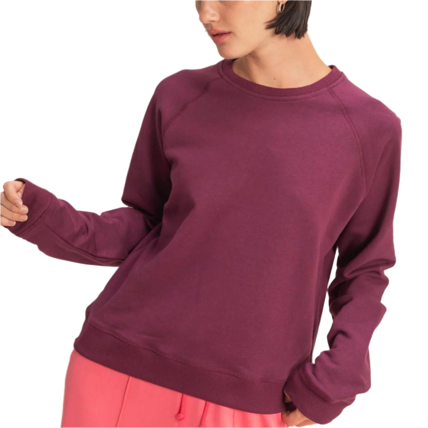 Woman wearing a purple sweatshirt and pink pants against a beige background