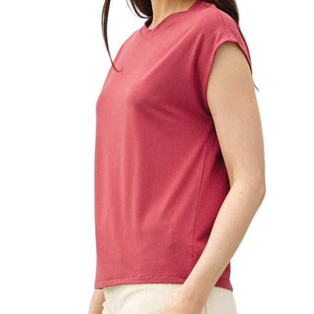 Woman wearing a pink top and white pants on a plain background
