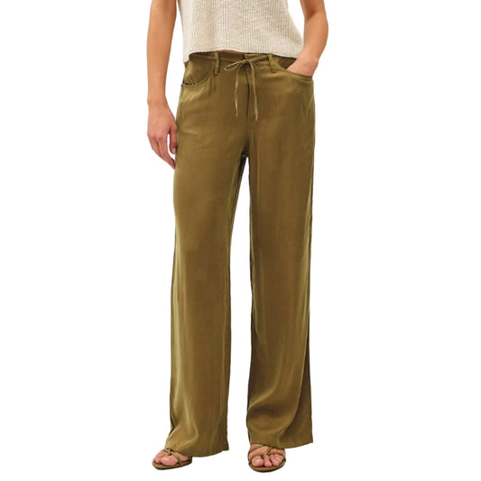 Woman wearing a white top and olive green pants on a plain background