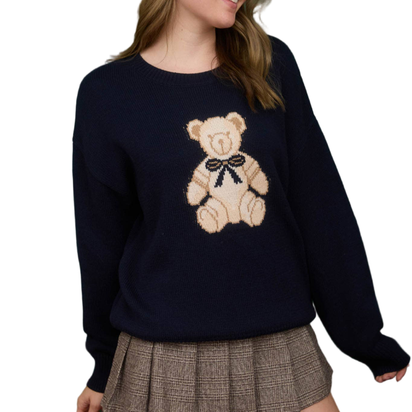 Woman wearing a navy sweater with a teddy bear design against a green background