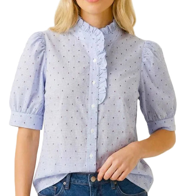 Woman wearing a light blue polka dot blouse and denim shorts on a white background