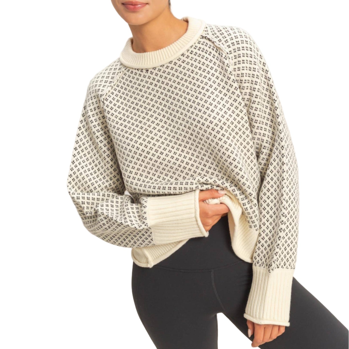 Woman wearing a patterned sweater and black pants against a plain background