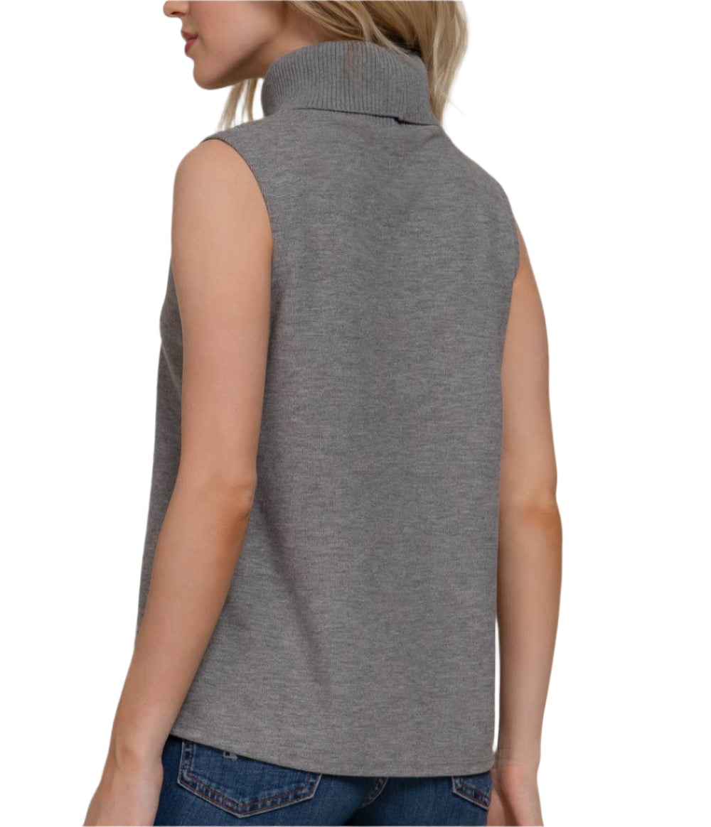 Woman wearing a gray sleeveless top and blue jeans on a plain background