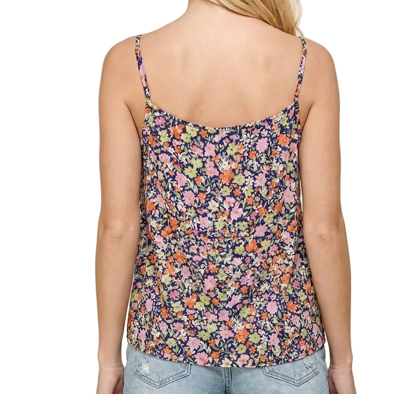 Woman wearing a floral tank top and denim shorts on a beige background