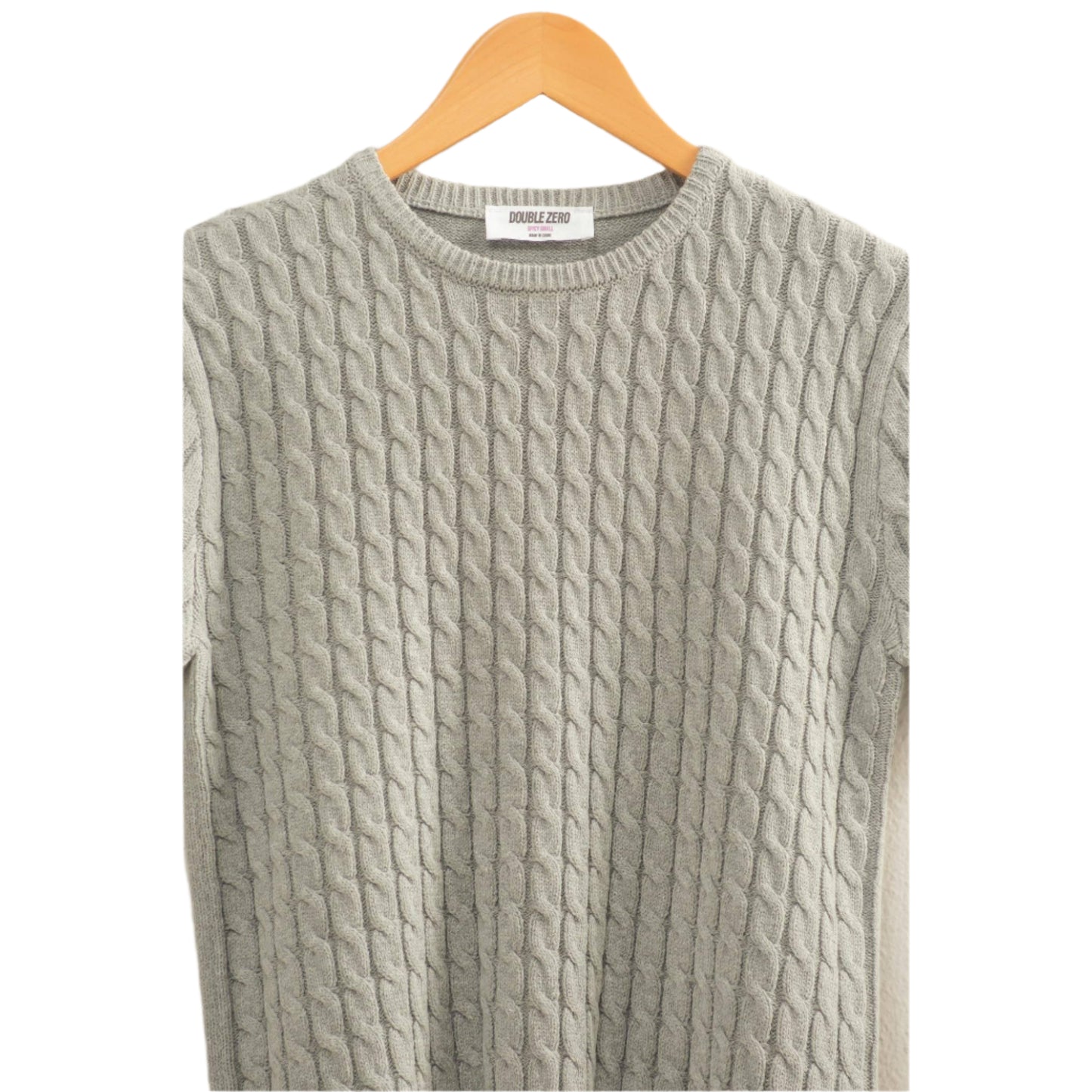 Gray cable knit sweater on a hanger against a light background