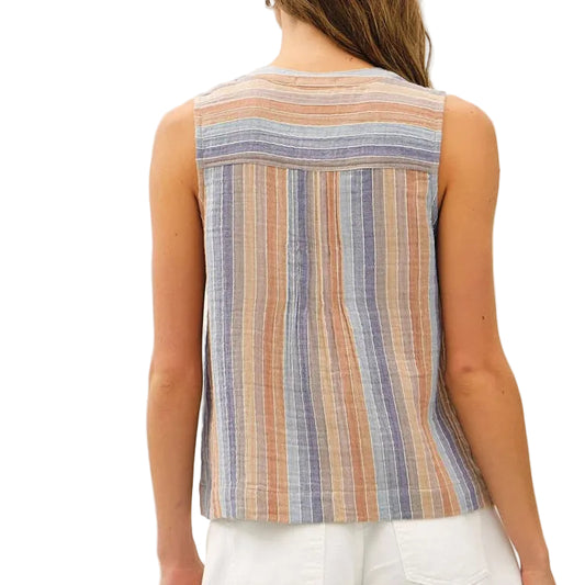 Woman wearing a striped sleeveless top and white shorts on a plain background