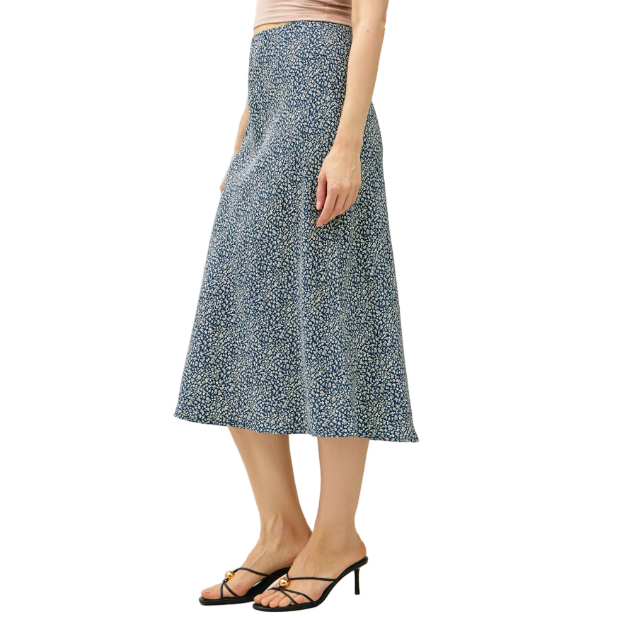 Woman wearing a beige tank top and blue patterned skirt on a white background