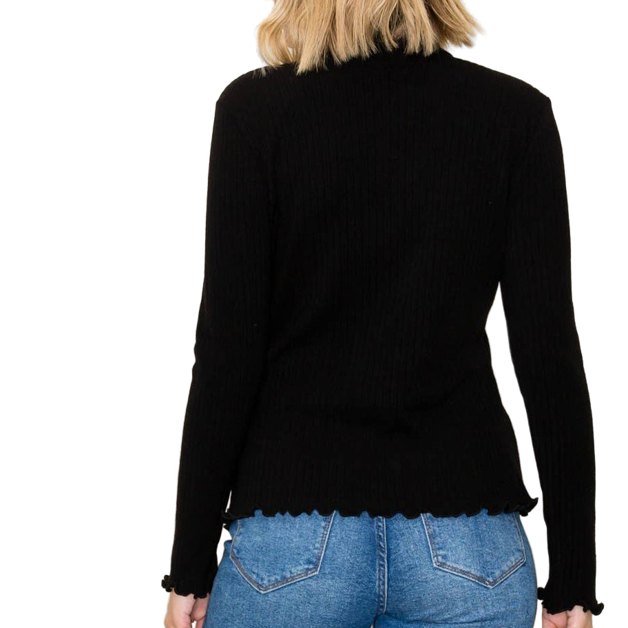 Person wearing a black long-sleeve top and blue jeans against a plain background