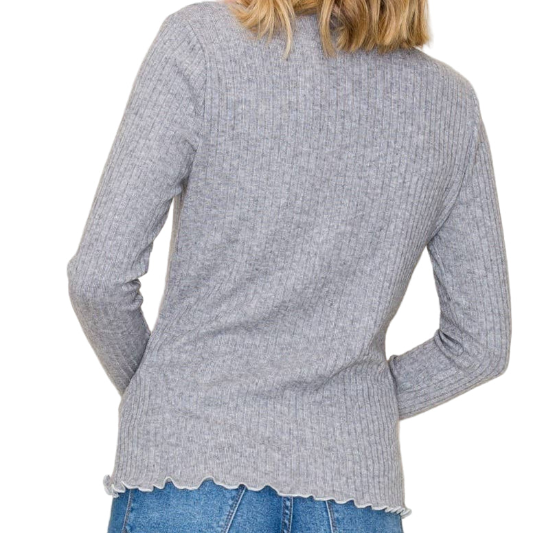 Woman wearing a gray sweater and blue jeans against a plain background