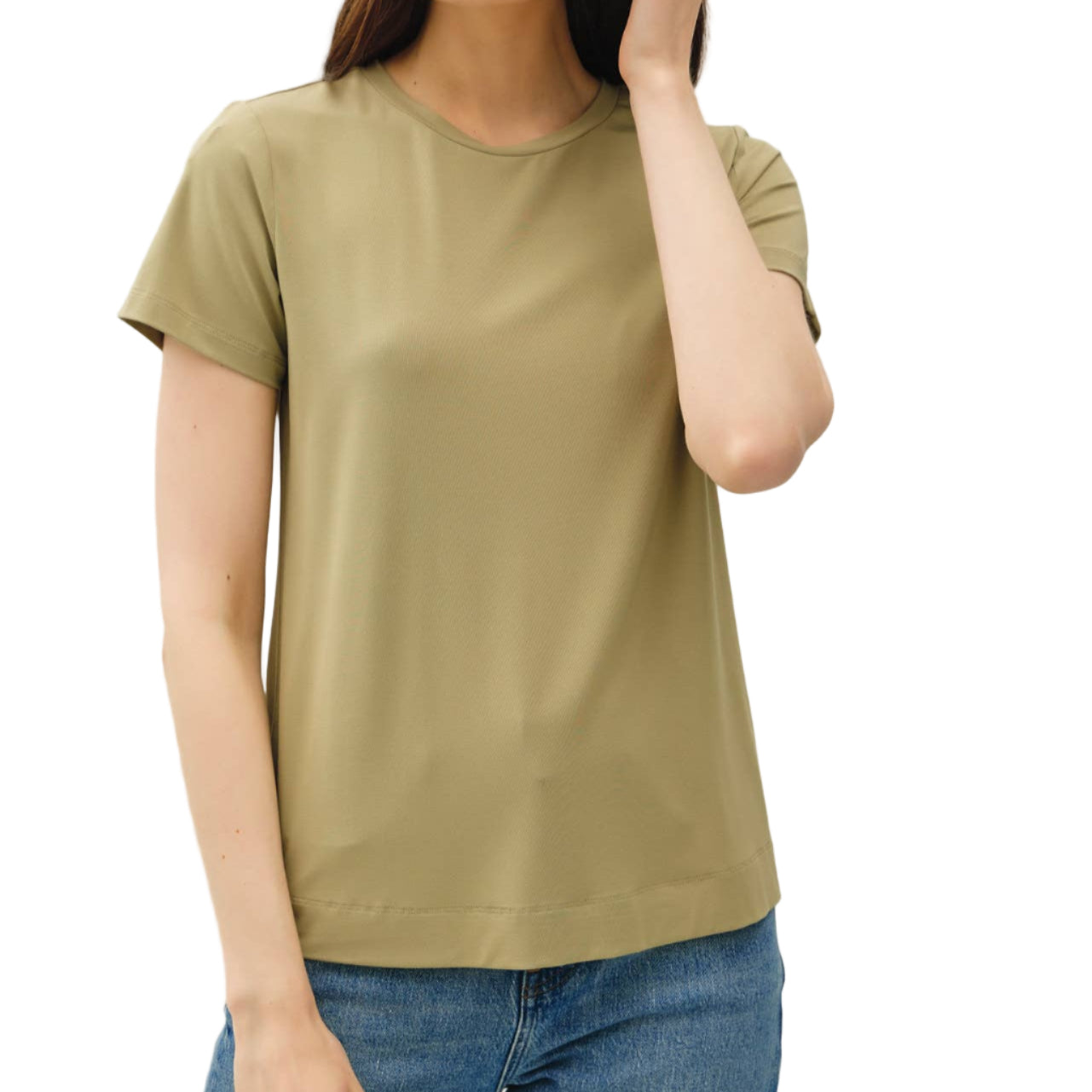 Woman wearing a green t-shirt and blue jeans against a plain background