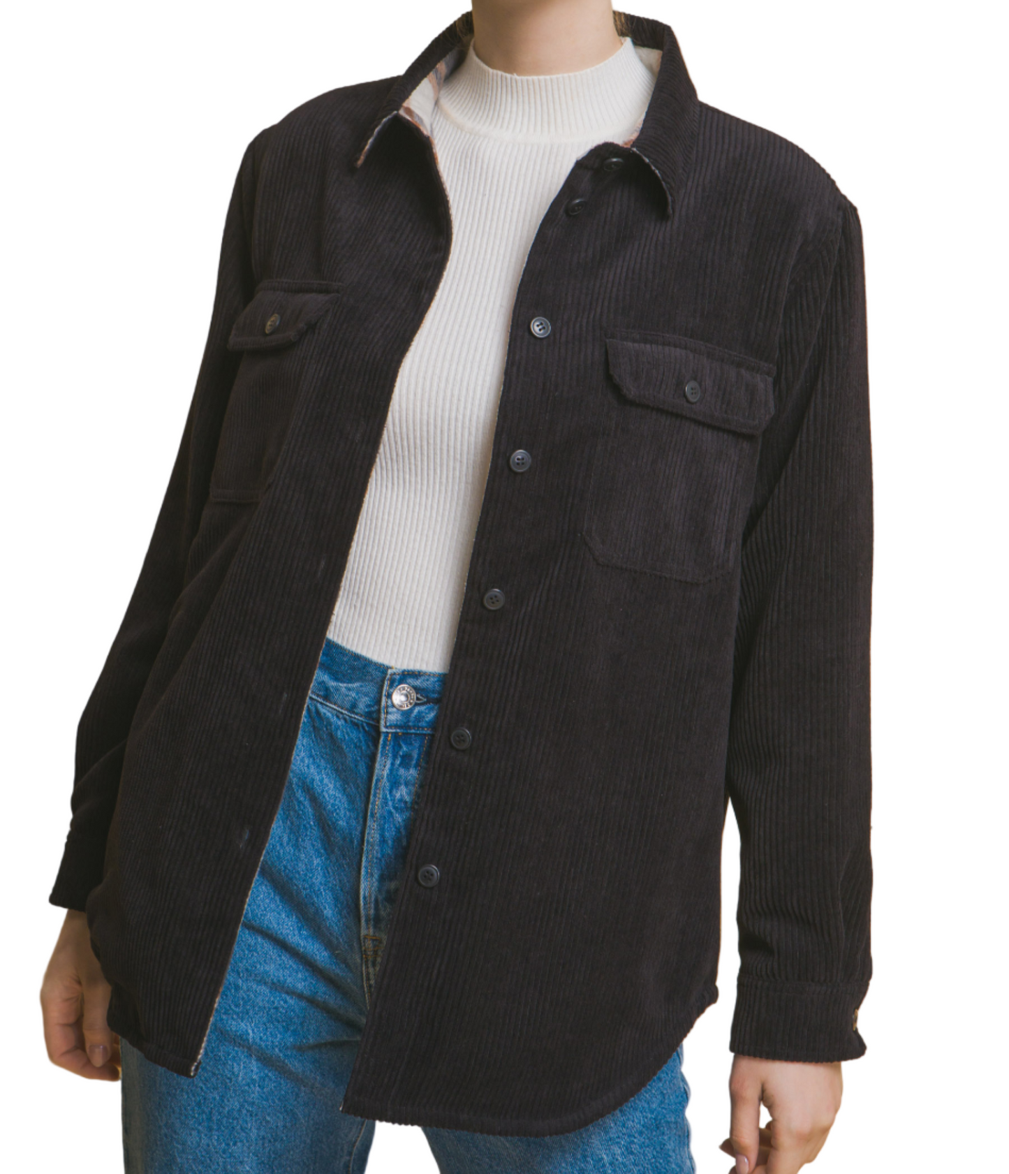 Person wearing a black shirt over a white sweater with blue jeans on a beige background