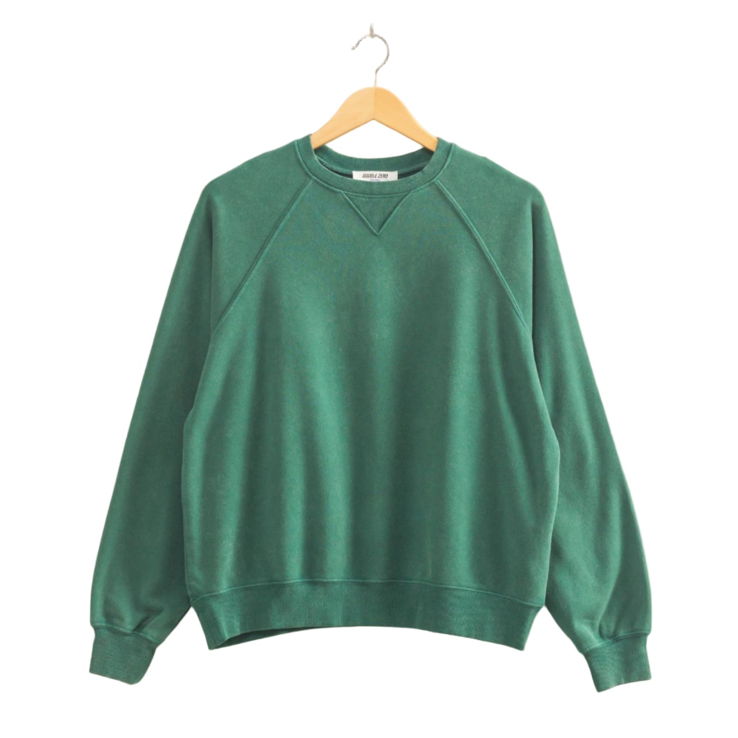 Green sweatshirt on a wooden hanger against a beige wall