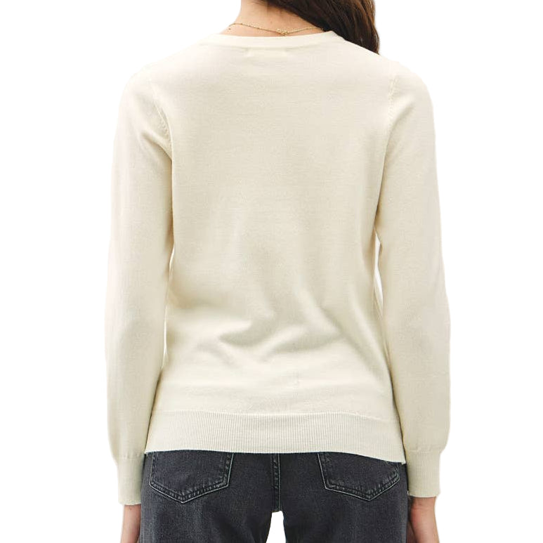 Person wearing a cream sweater and dark jeans against a white background