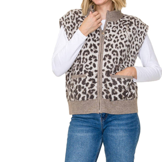 Woman wearing a leopard print vest over a white long-sleeve shirt and blue jeans on a beige background