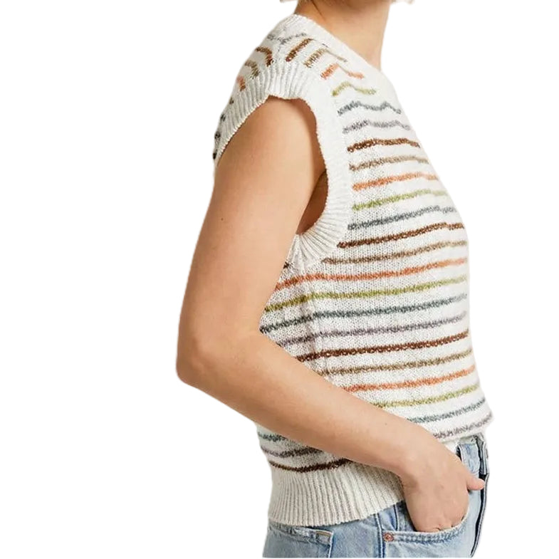 Woman wearing a sleeveless striped sweater and jeans on a plain background