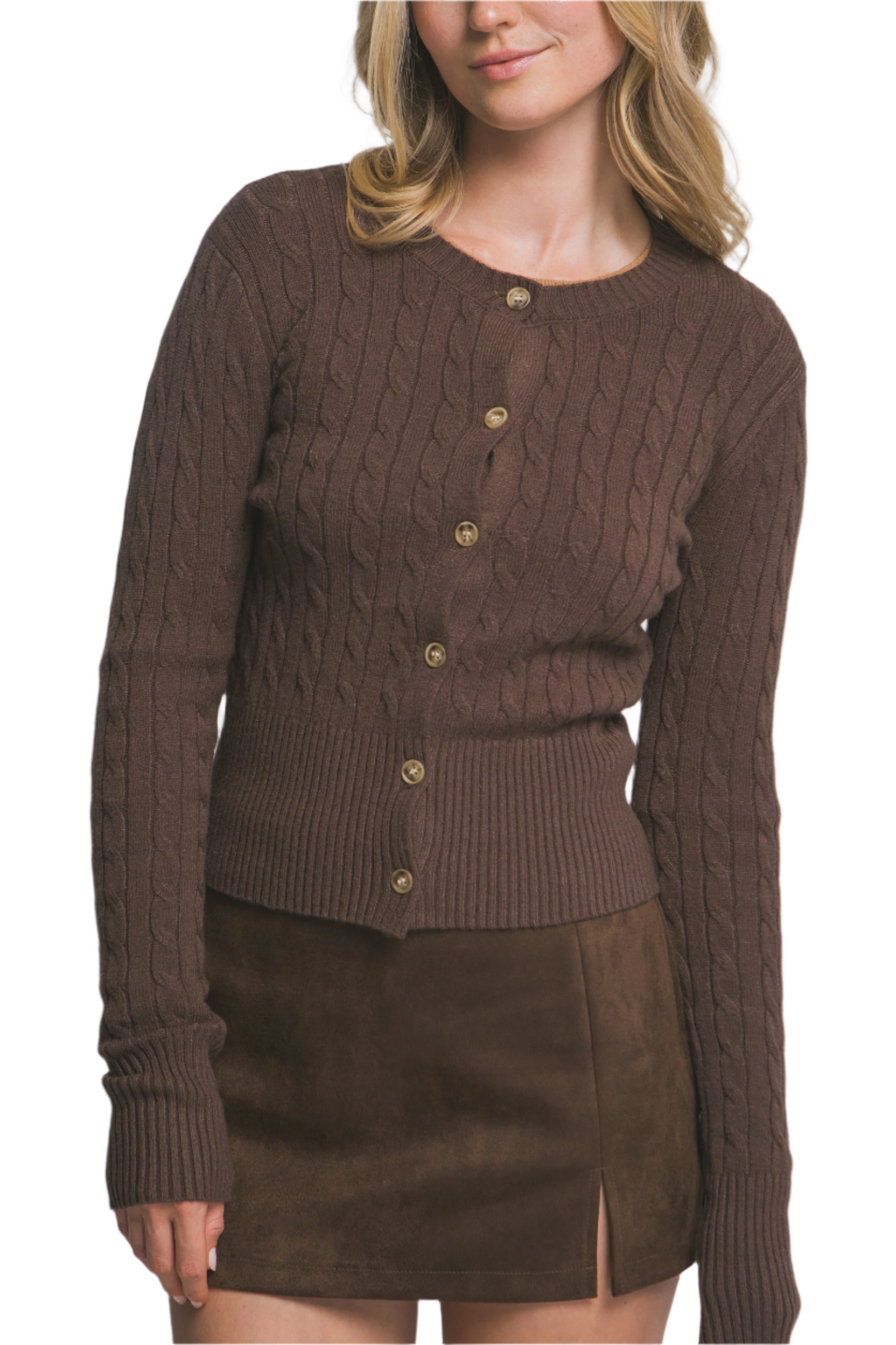 Woman wearing a brown cable knit cardigan over a brown suede skirt on a plain background