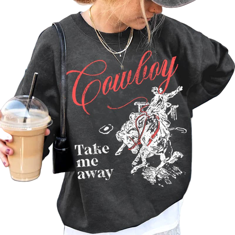 Person wearing a black sweatshirt with 'Cowboy Take me away' text and graphic, holding a drink.
