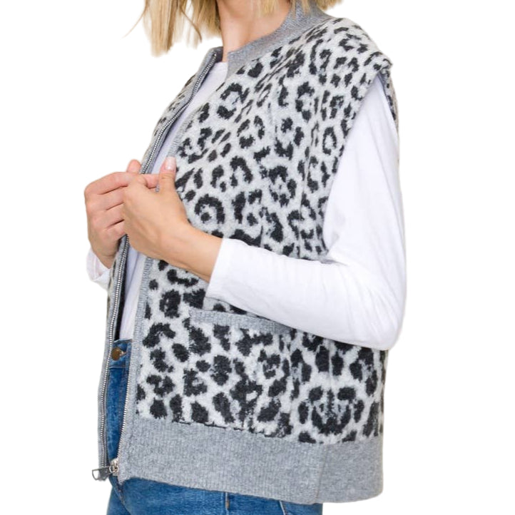 Woman wearing a leopard print vest over a white shirt with blue jeans on a beige background