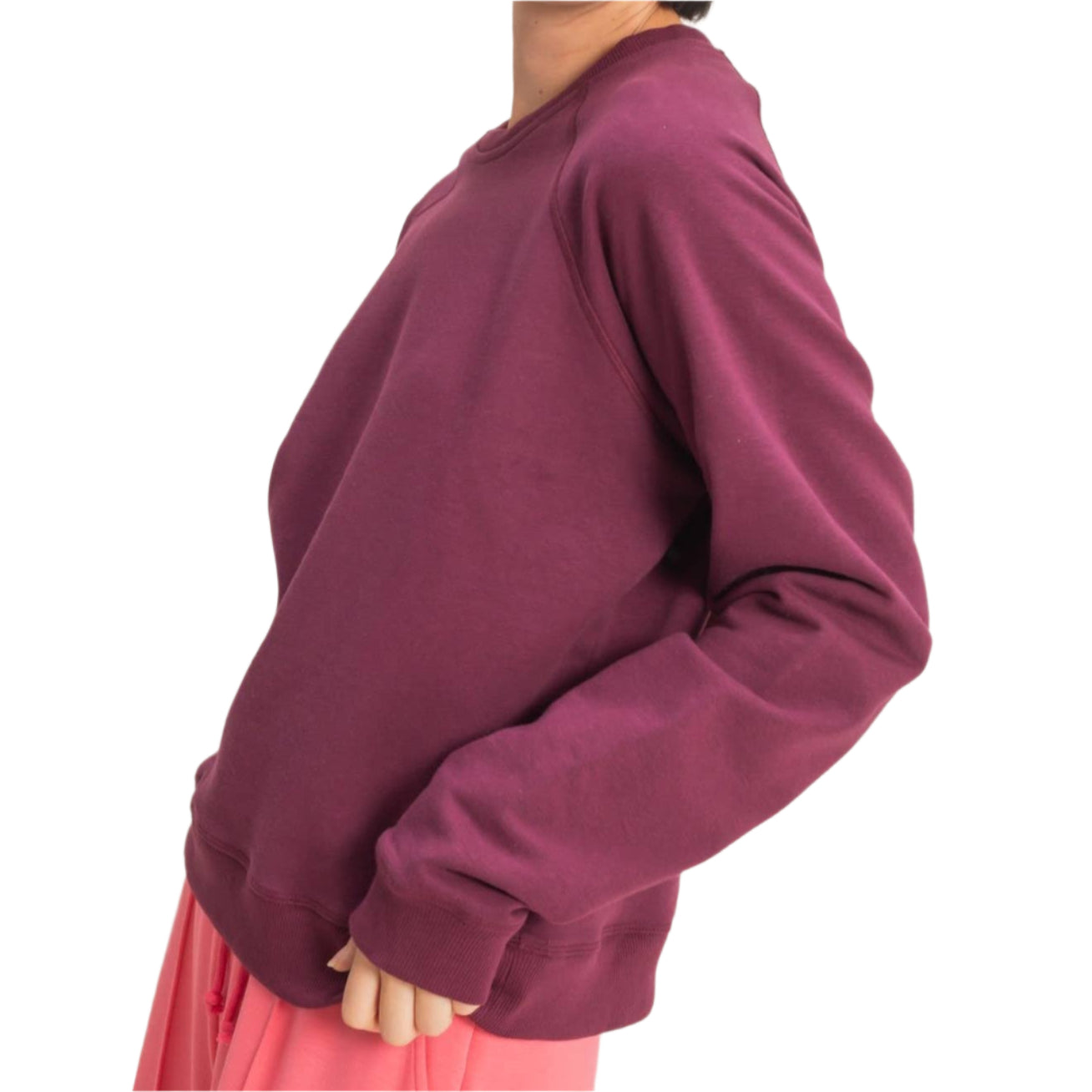 Woman wearing a maroon sweater and pink pants against a beige background