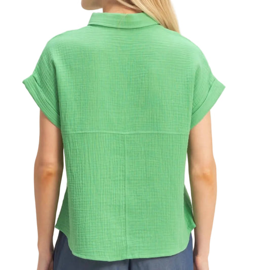 Woman wearing a green short-sleeve top and blue shorts on a beige background