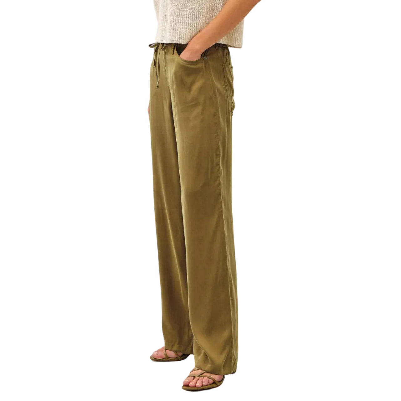 Woman wearing a white top and green pants against a white background