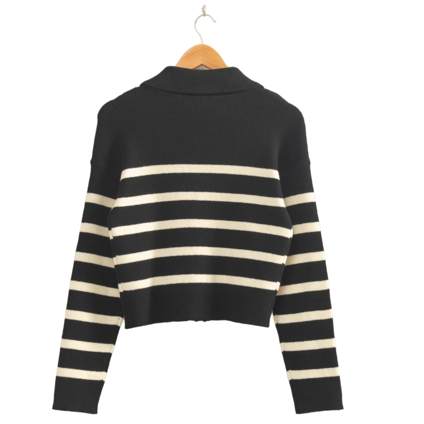 Black and white striped sweater on a hanger against a beige wall