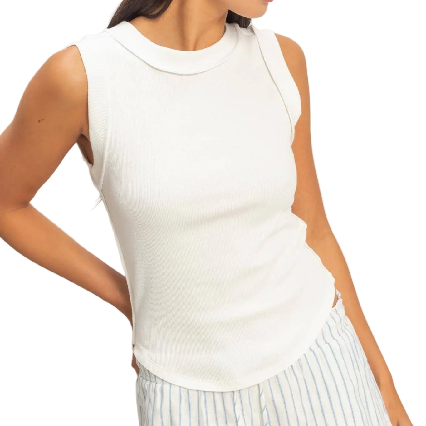 Woman wearing a white sleeveless top and light-colored pants against a plain background