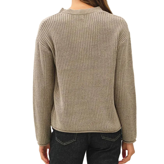 A woman viewed from the back wearing a beige ribbed knit sweater, dark blue flared jeans, and black sneakers against a plain white studio background.
