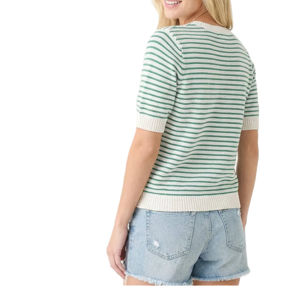 Woman wearing a green and white striped sweater with denim shorts on a light gray background
