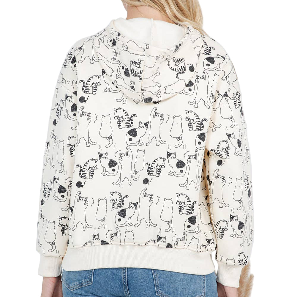 Person wearing a hoodie with cat pattern and blue jeans indoors.