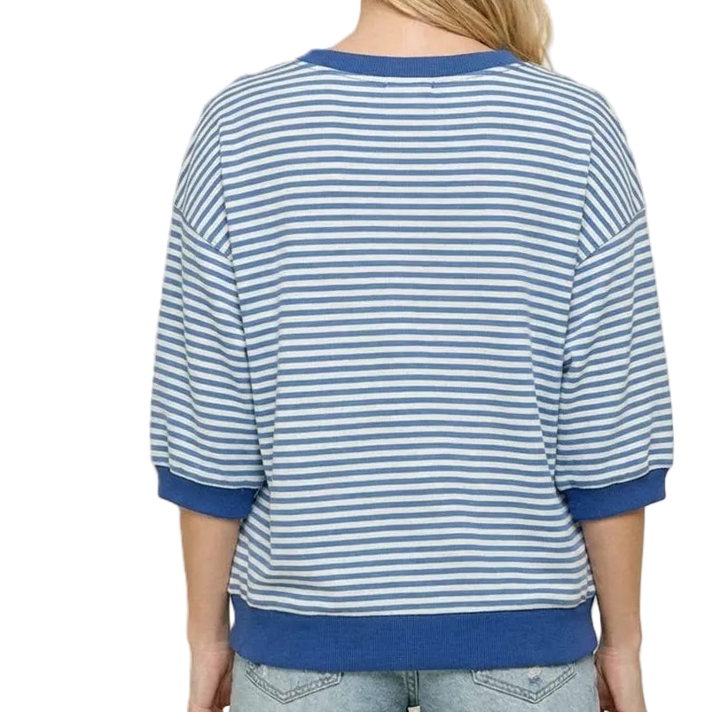 Person wearing a blue and white striped shirt with denim shorts on a beige background