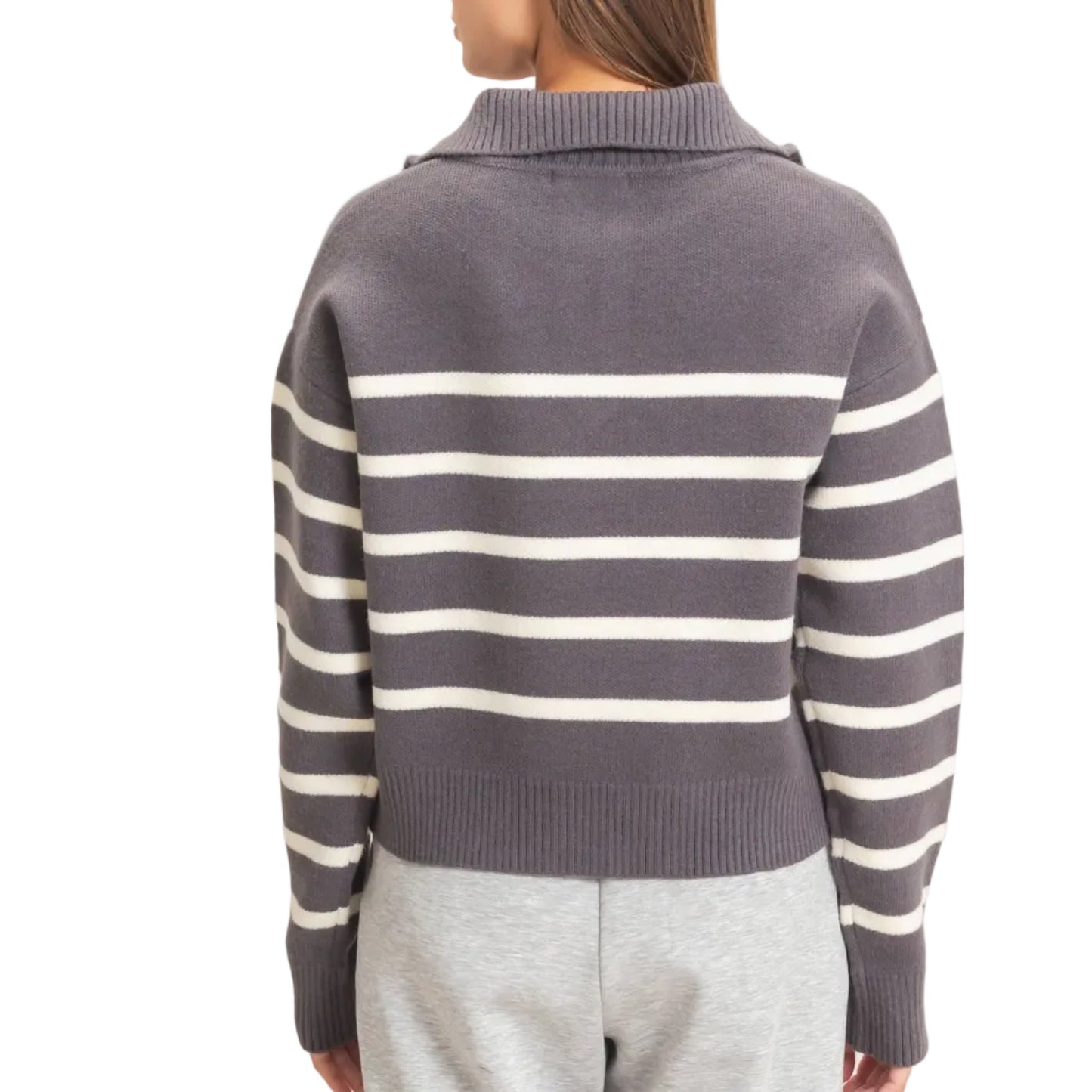A woman shown from the back wearing a gray knit sweater with horizontal cream stripes and light gray sweatpants, against a plain off-white studio background.