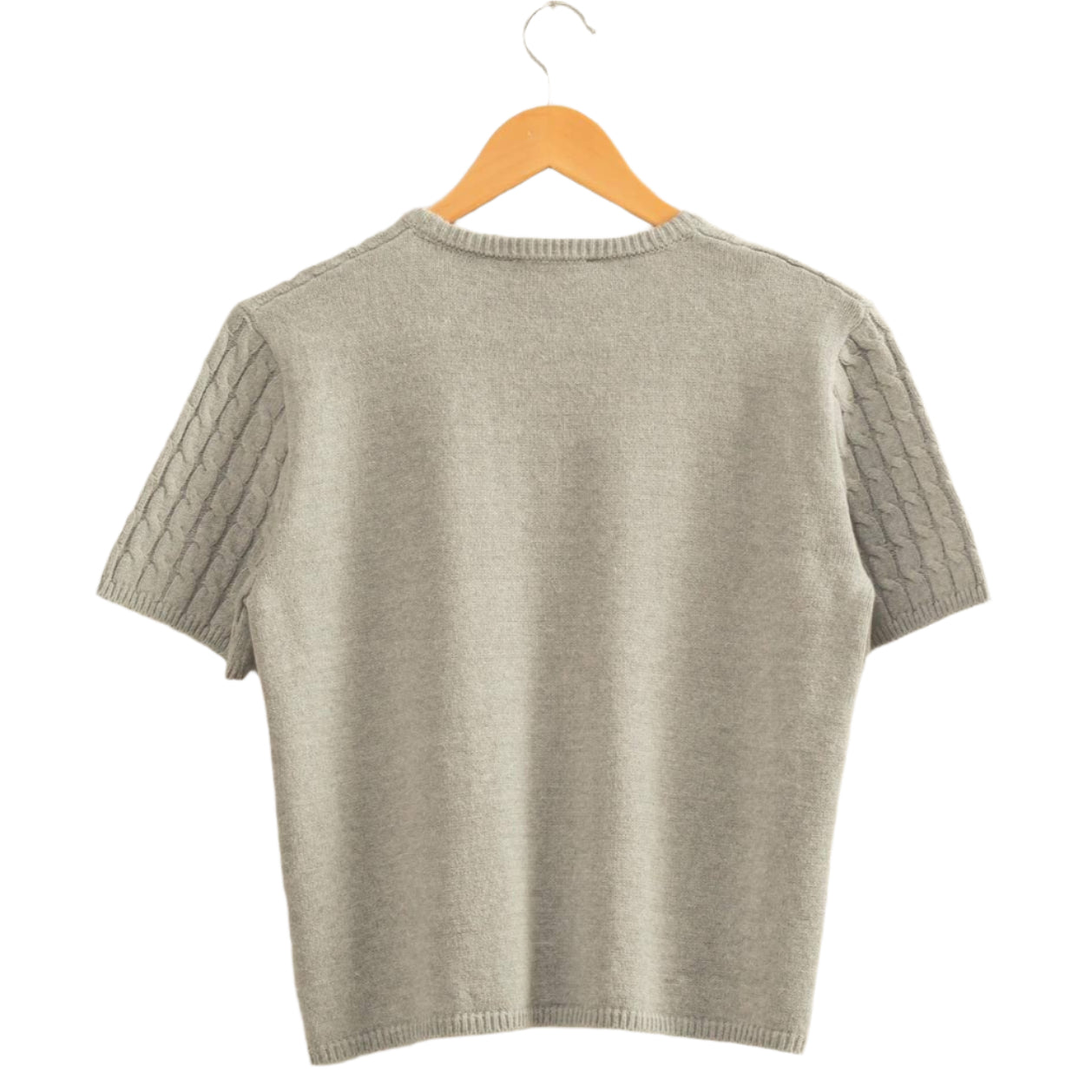 Gray sweater on a hanger against a beige wall