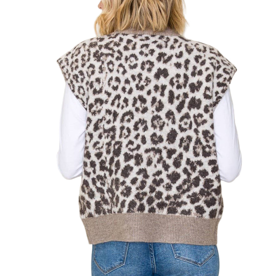 Person wearing a leopard print vest over a white shirt and blue jeans on a beige background