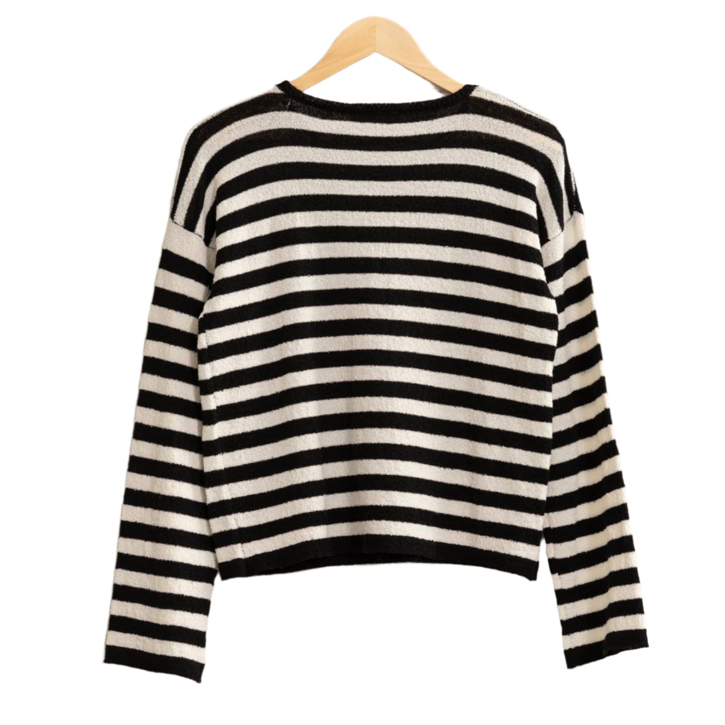 Black and white striped sweater on a hanger against a beige background