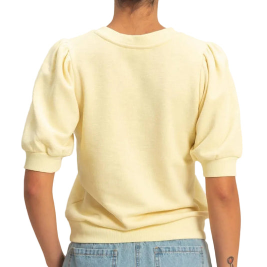 Person wearing a light yellow sweater and blue jeans on a plain background