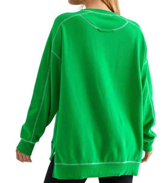 Person wearing a green sweatshirt with white accents on a plain background