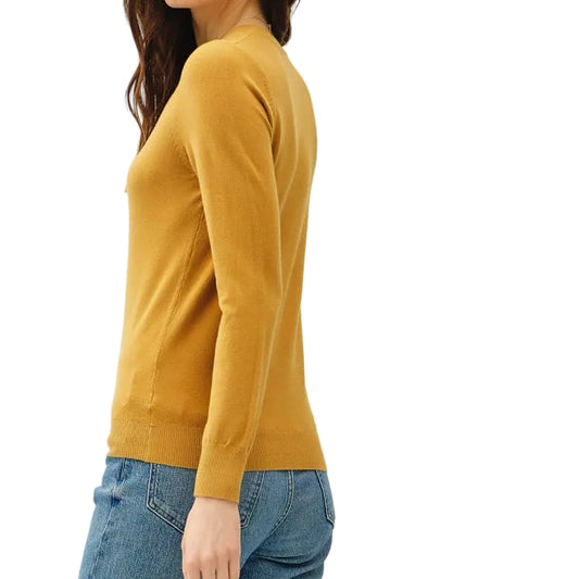 Woman wearing a mustard yellow sweater and blue jeans on a white background
