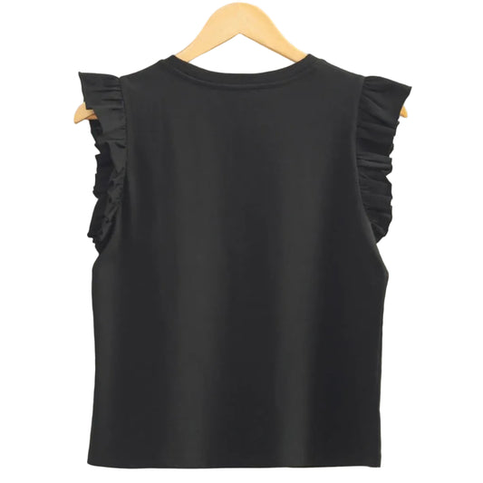 Black sleeveless top with ruffled shoulders on a hanger against a beige wall.