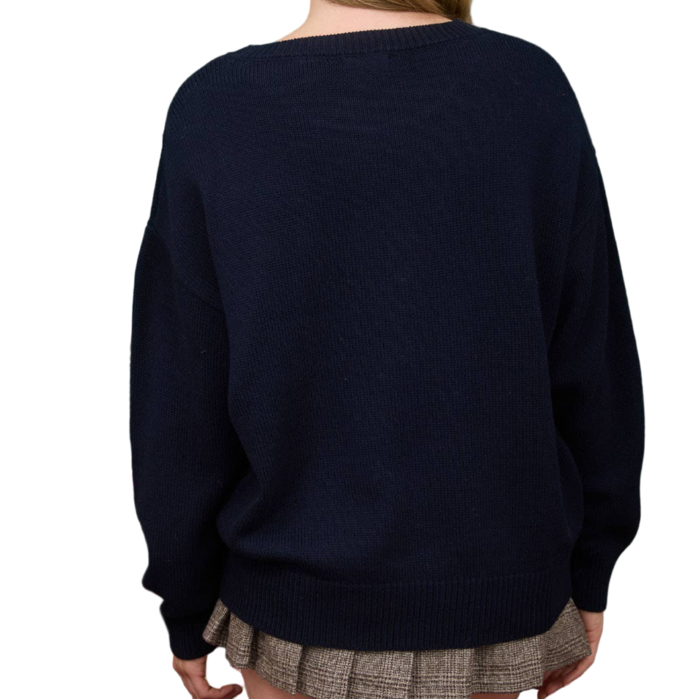 Person wearing a navy sweater and plaid skirt against a green background with a small Christmas tree.