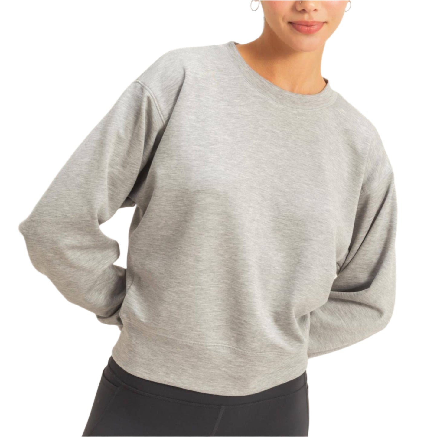 Woman wearing a gray sweater and black leggings against a plain background