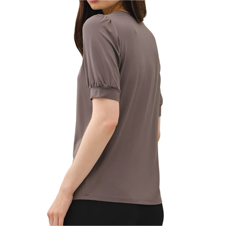 Woman wearing a brown top and black pants on a white background