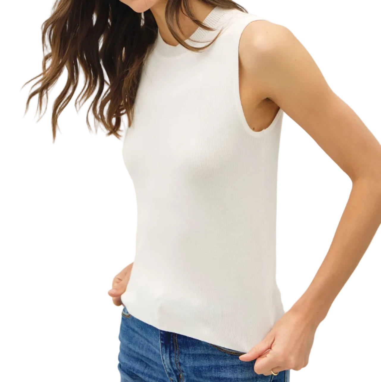 Woman wearing a white sleeveless top and blue jeans against a plain background