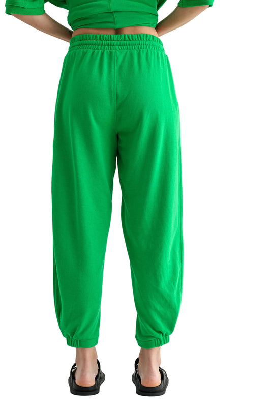 Person wearing green pants and a green top on a light gray background