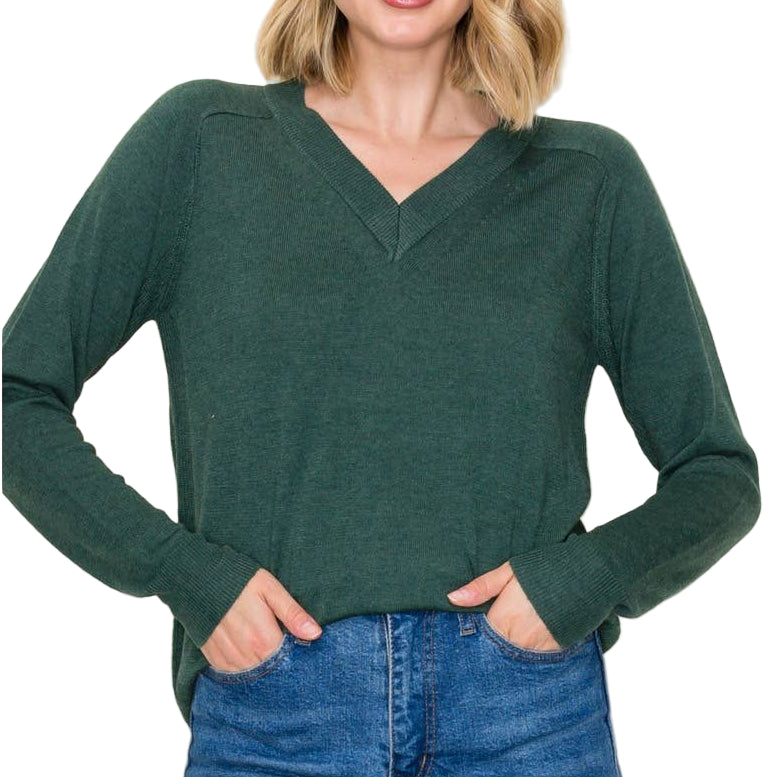 Woman wearing a green sweater and blue jeans against a white background