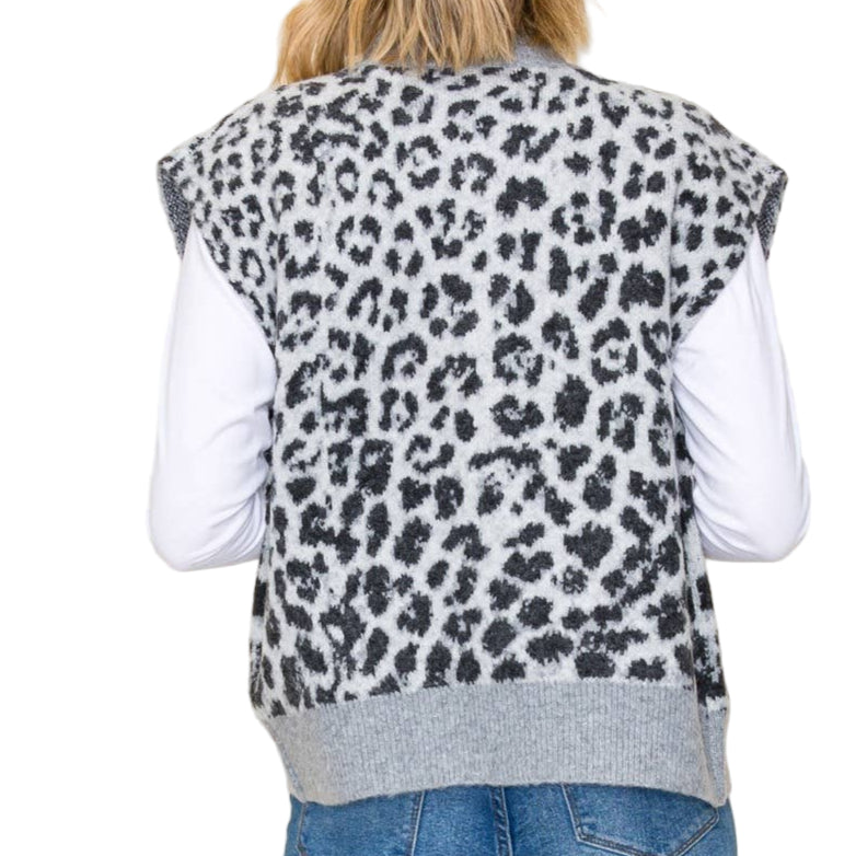 Person wearing a leopard print vest over a white shirt and blue jeans on a beige background